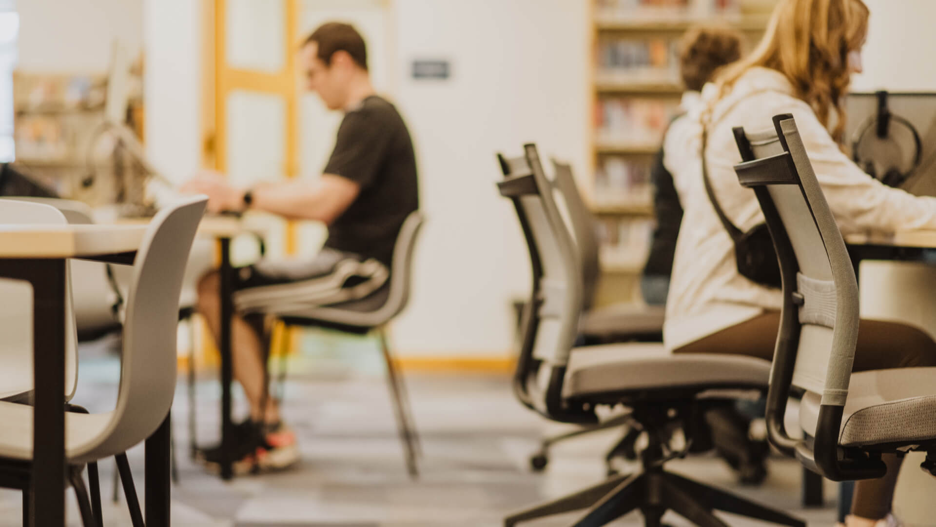 People sitting at tables working in a library.