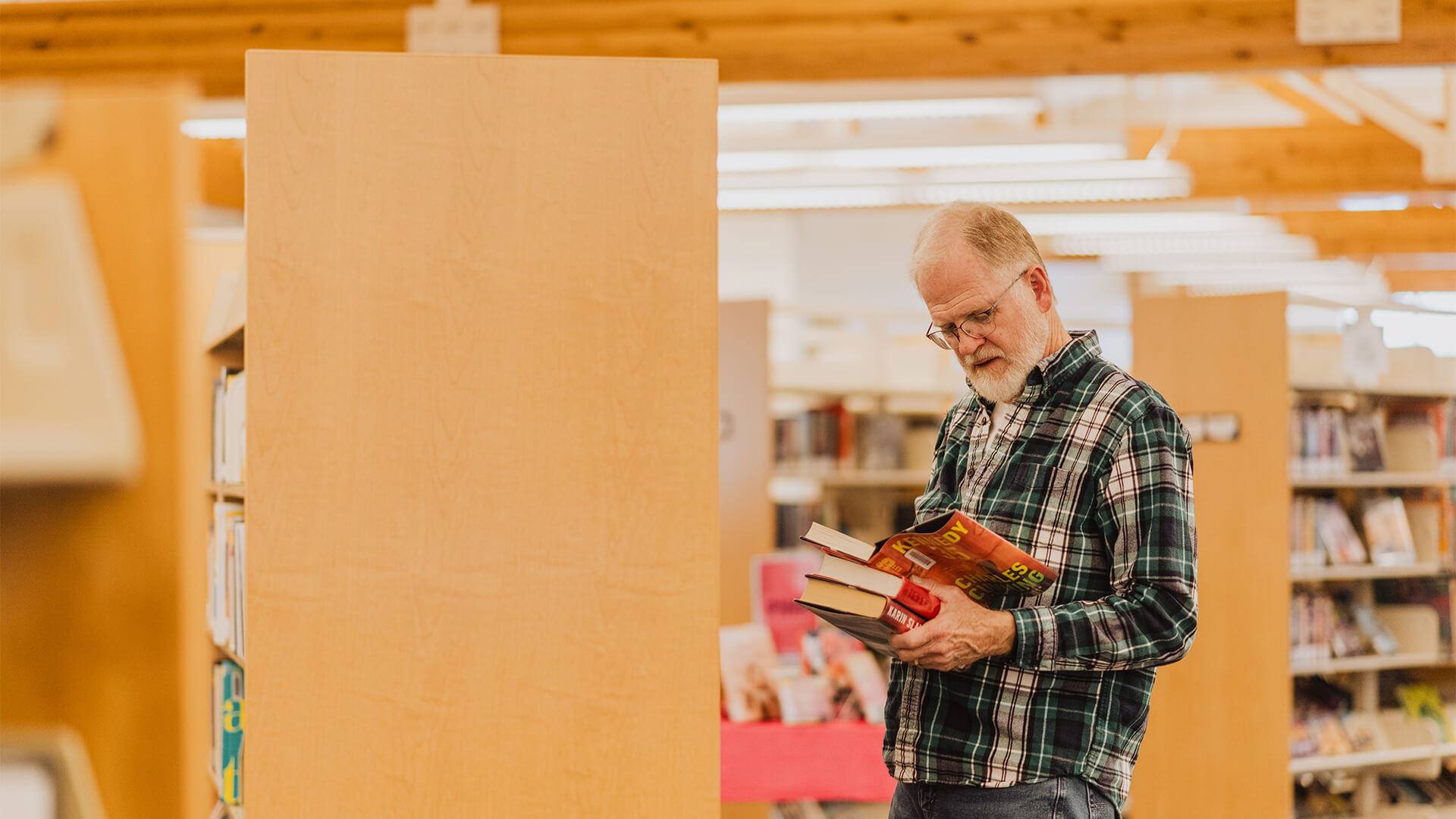 Man in library browsing shelves and holding books