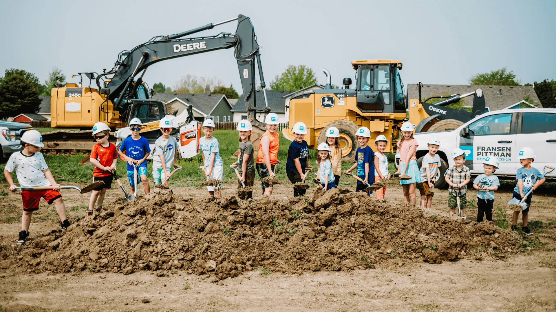 Kids shoveling dirt at a groundbreaking.