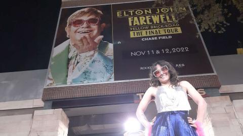 Woman standing in front of an Elton John Billboard.