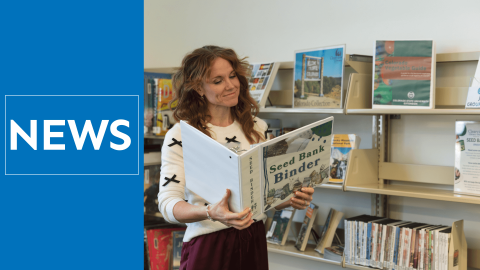 Woman standing and reading in a library by shelves