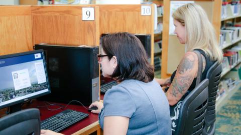 Laptops & Computer Stations Two women at desktops in a library.