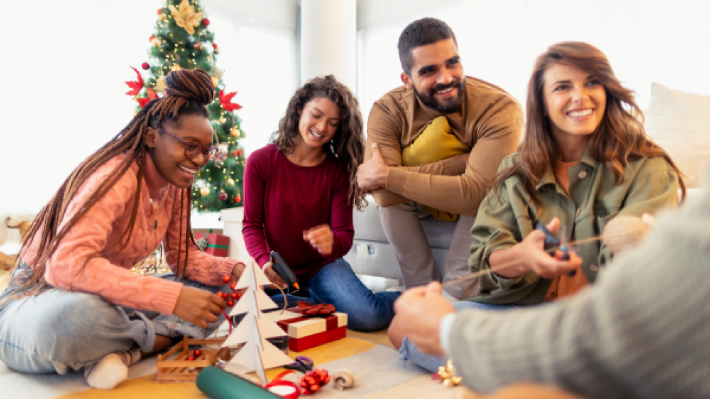 Group of people sitting and wrapping gifts.